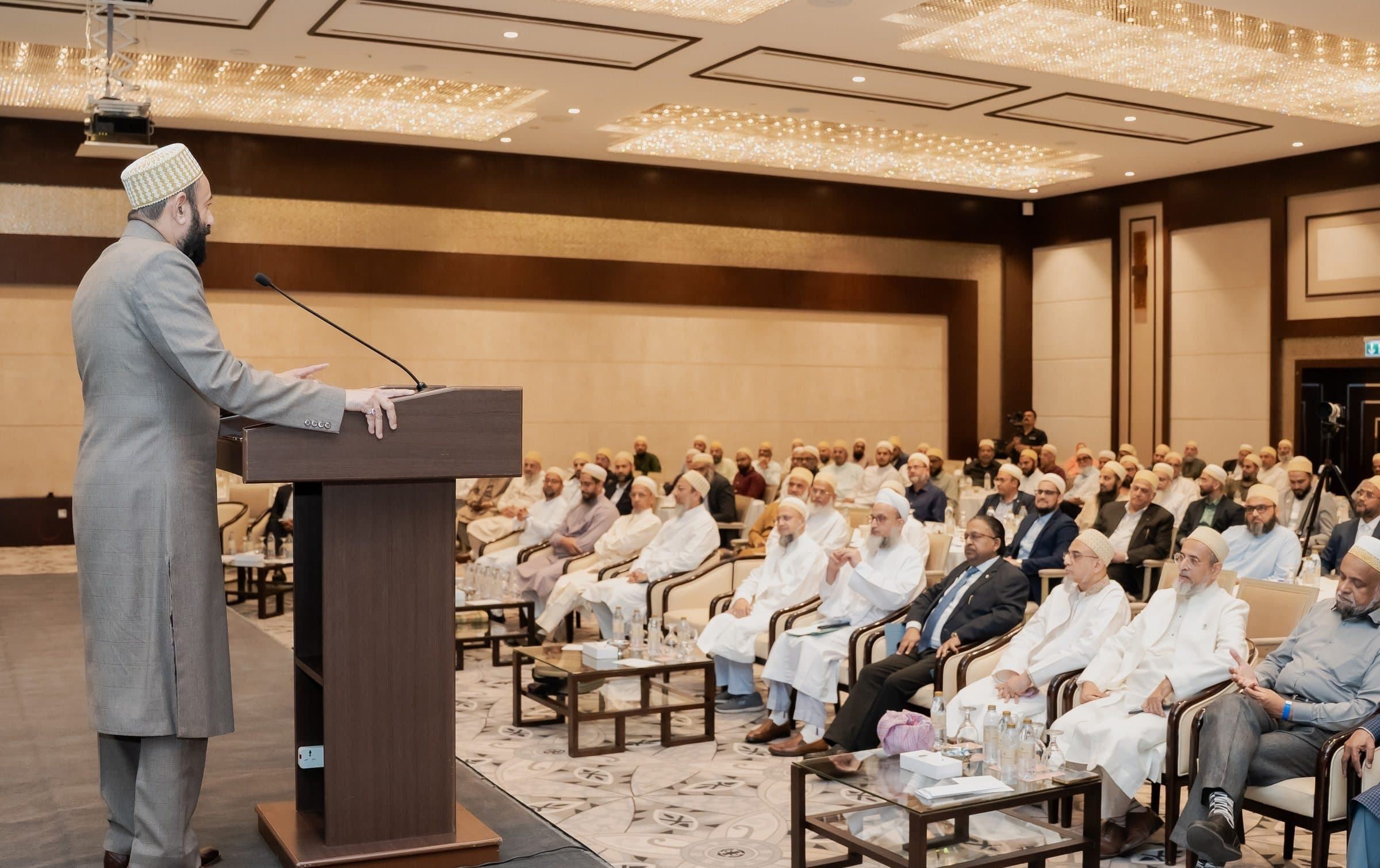 Speaker at a podium on a stage facing a full room of seated guests