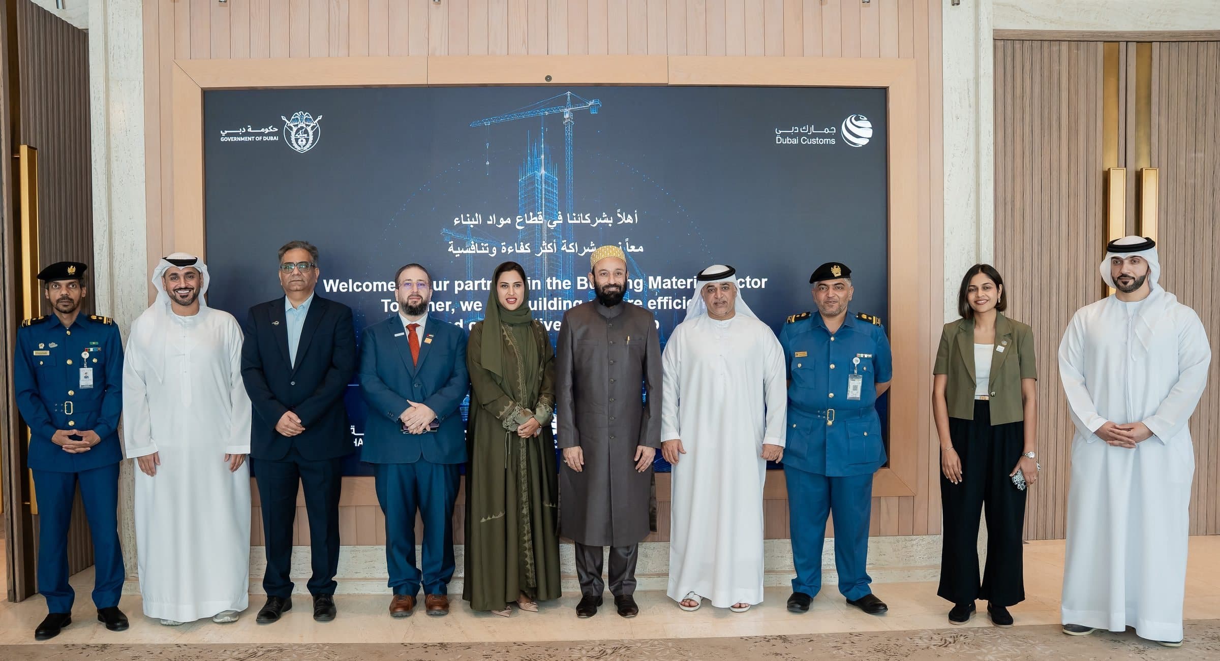Officials and members, some in customs uniform, standing on a stage before a large screen
